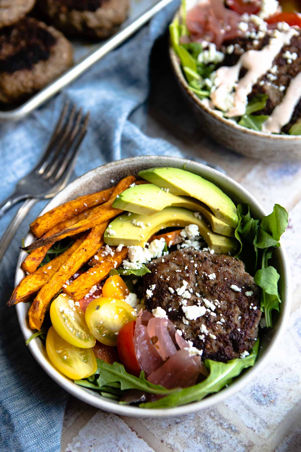 hamburger bowls topped with avocado and feta cheese and a special burger sauce