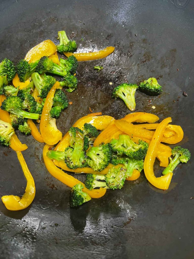broccoli, peppers being cooked in a wok