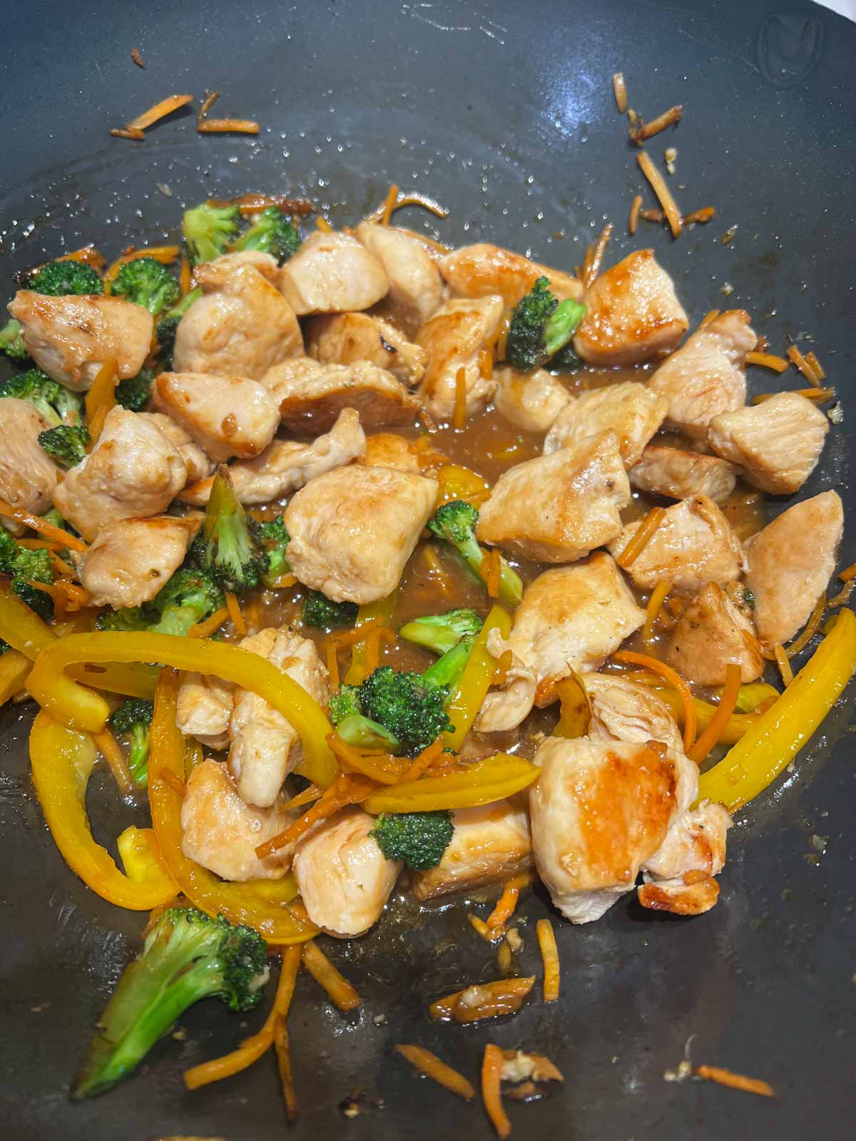 chicken and veggies added to a wok to cook with a homemade teriyaki sauce