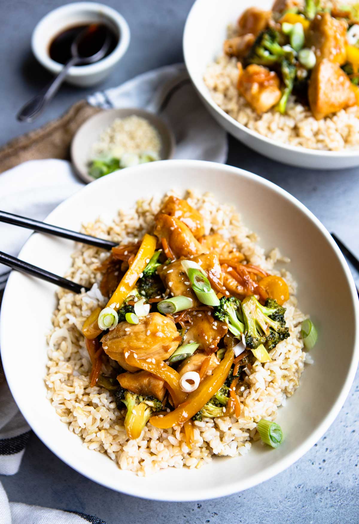 chicken teriyaki bowls with brown rice and garnished with green onions in large deep white bowls