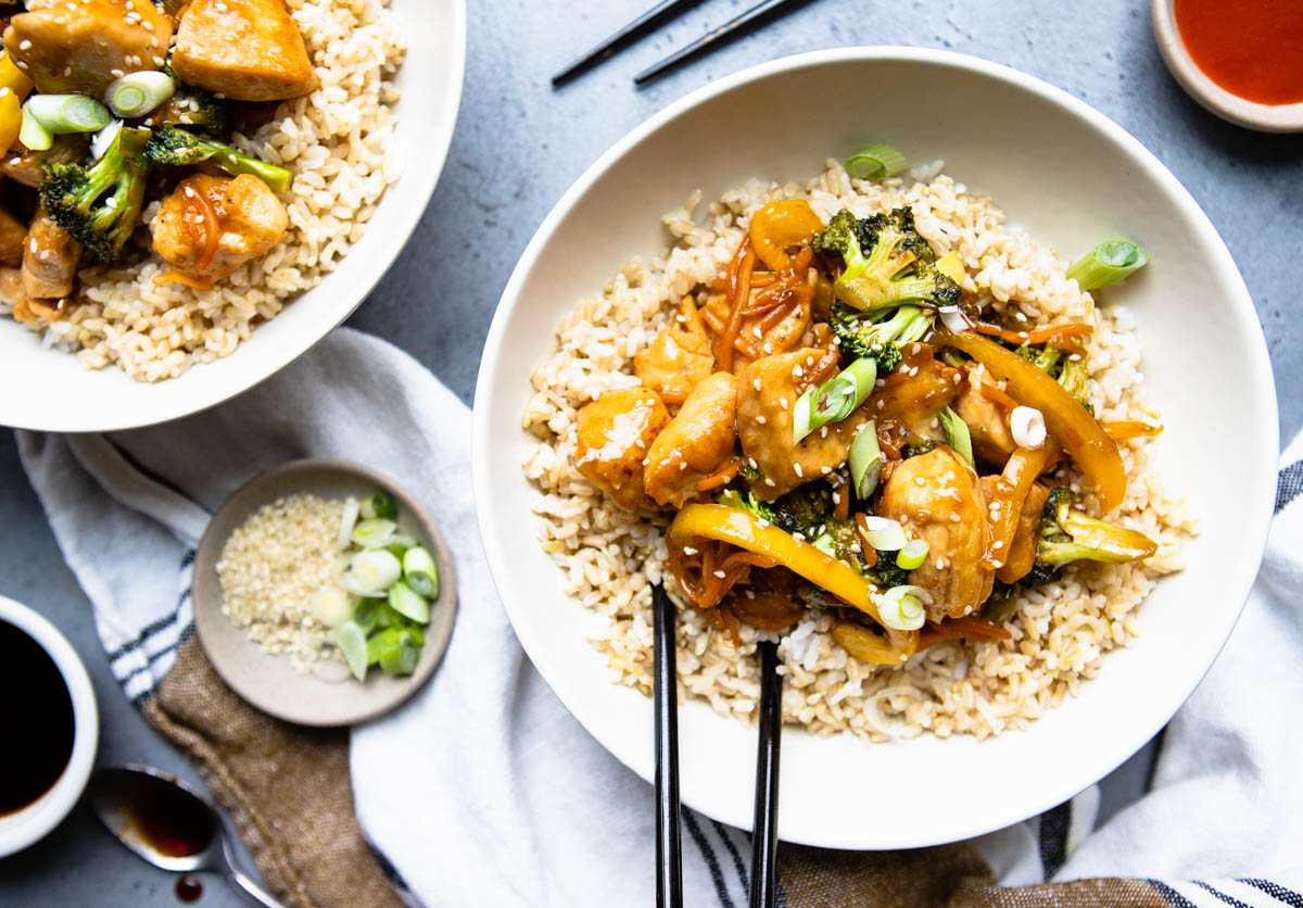 2 large white bowls filled with chicken teriyaki and veggies and garnished with green onions and sesame seeds