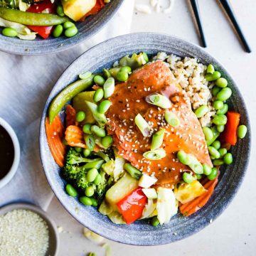 teriyaki salmon bowls loaded with vegetables, rice, edamame and garnished with sesame seeds