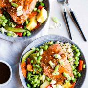 2 gray bowls filled with rice, vegetables, pineapple and salmon teriyaki