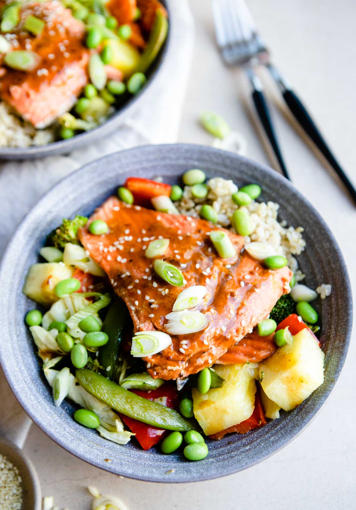 gray bowl filled with vegetables and pineapple and salmon teriyaki 