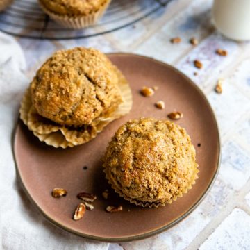 brown plate with 2 banana protein muffins and pieces of pecan
