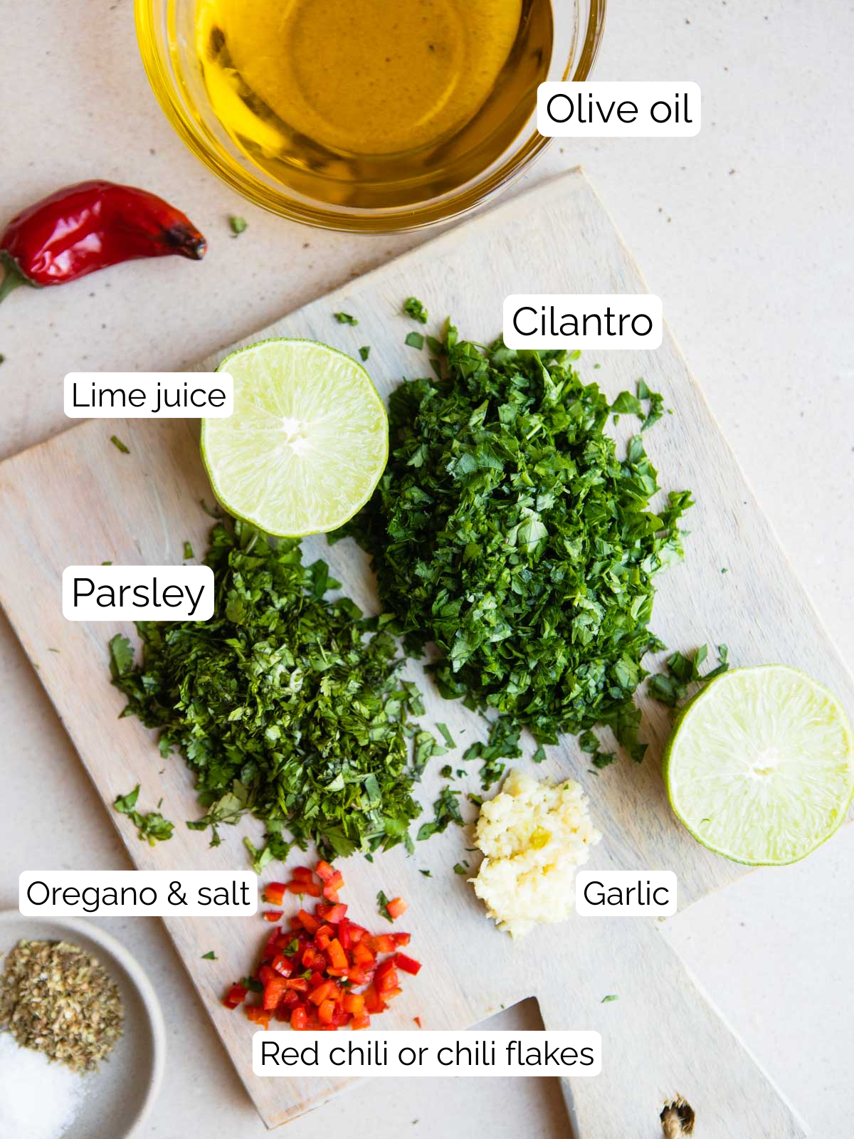 ingredients to make a cilantro chimichurri sauce all prepared and placed on a small wooden board