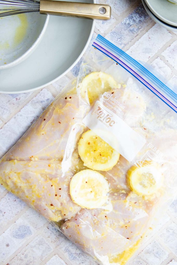a Ziploc freezer bag filled with a citrus marinade and chicken breasts 