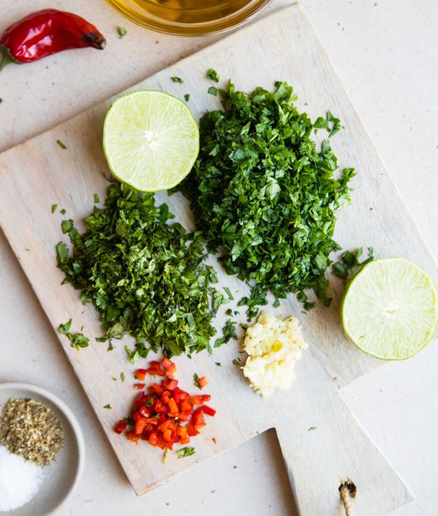 chopped herbs and minced garlic and red pepper on a wood board