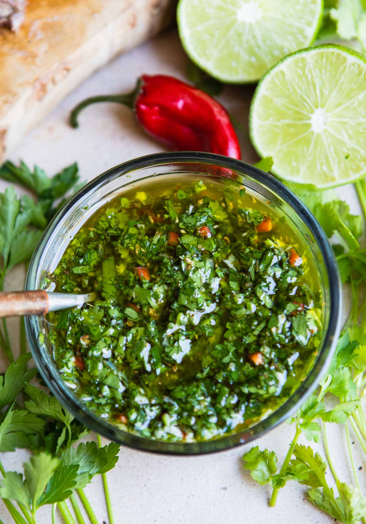 cilantro chimichurri sauce in a glass bowl with a wooden spoon