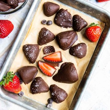 a parchment lined baking tray filled with chocolate dipped frozen strawberries