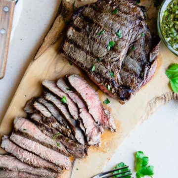 grilled top sirloin steaks on a wooden cutting board sliced into thin pieces