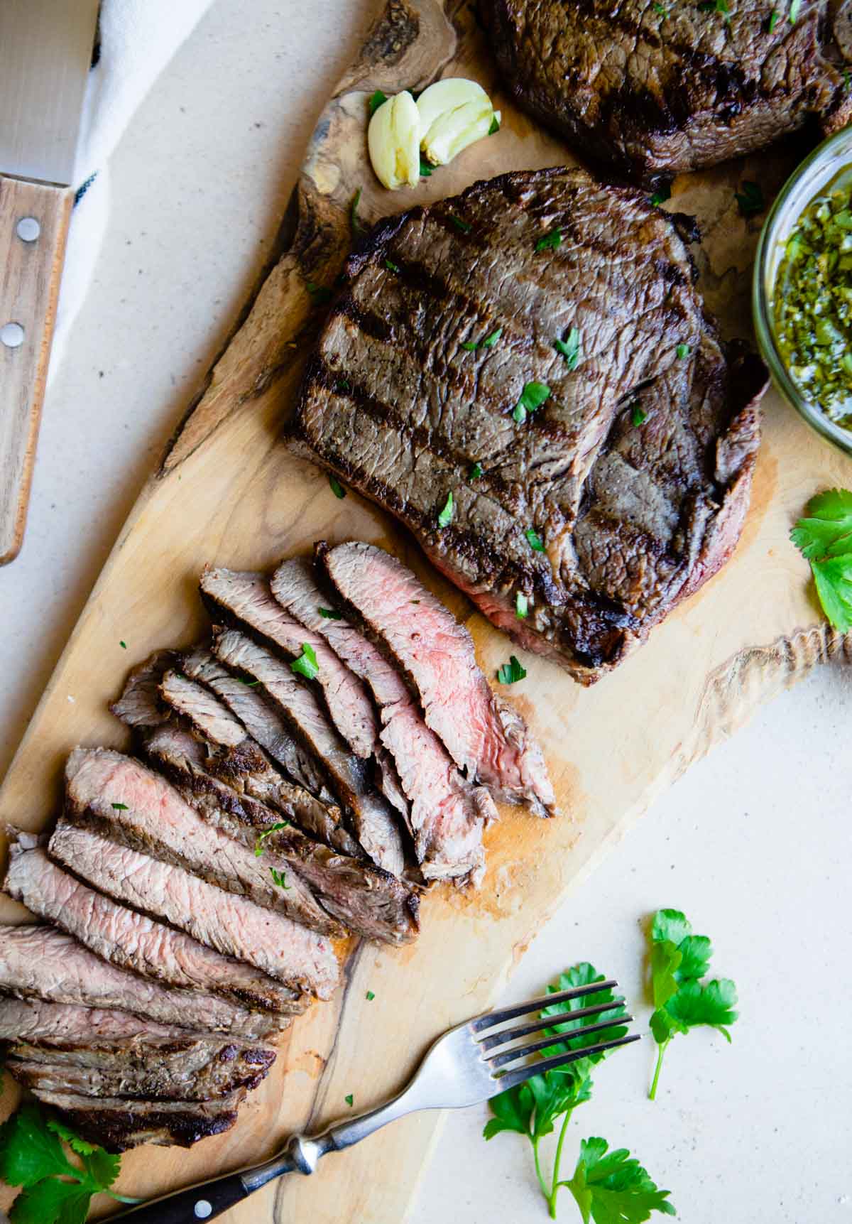 grilled top sirloin steaks on a wooden cutting board sliced into thin pieces