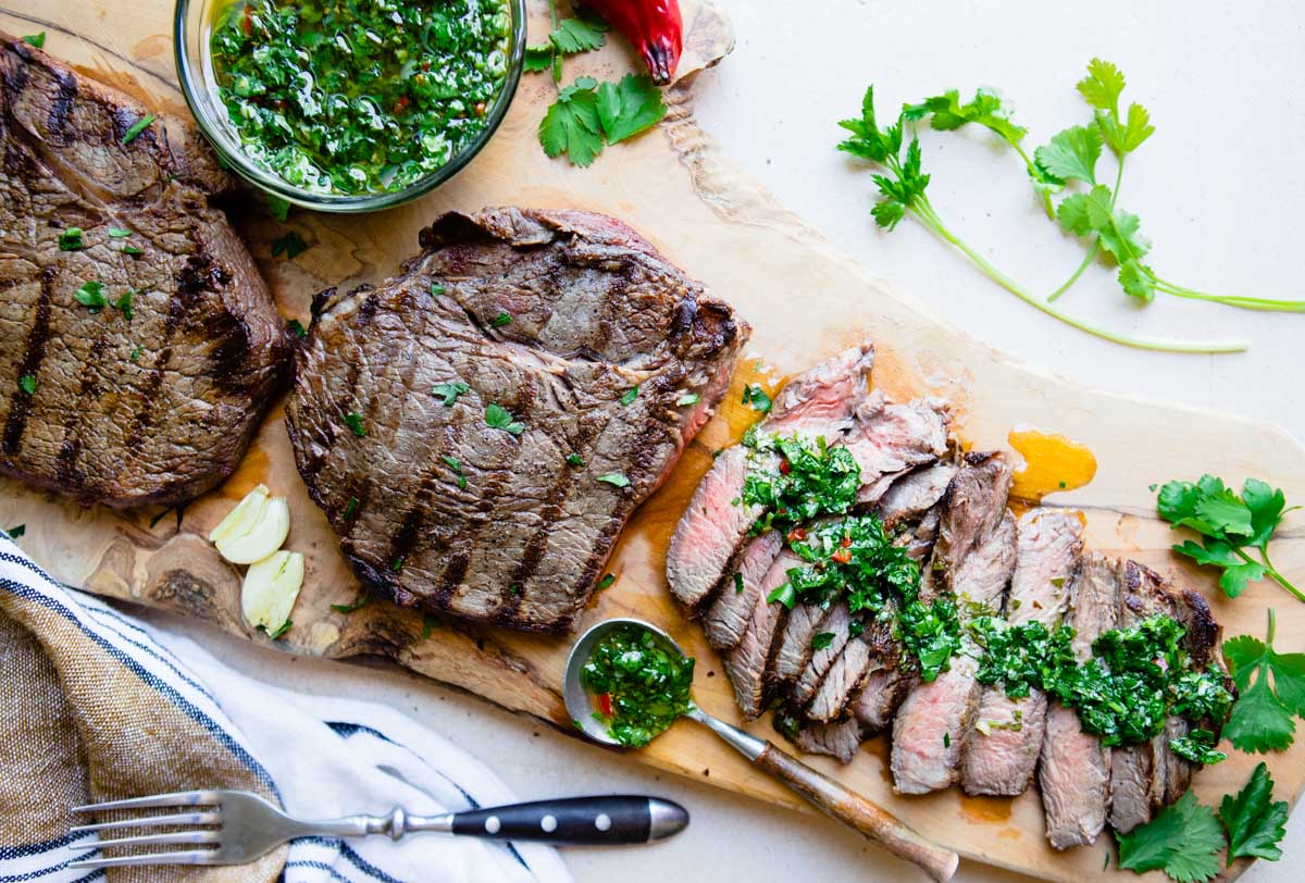 sliced top sirloin steak with cilantro chimichurri sauce drizzled all over