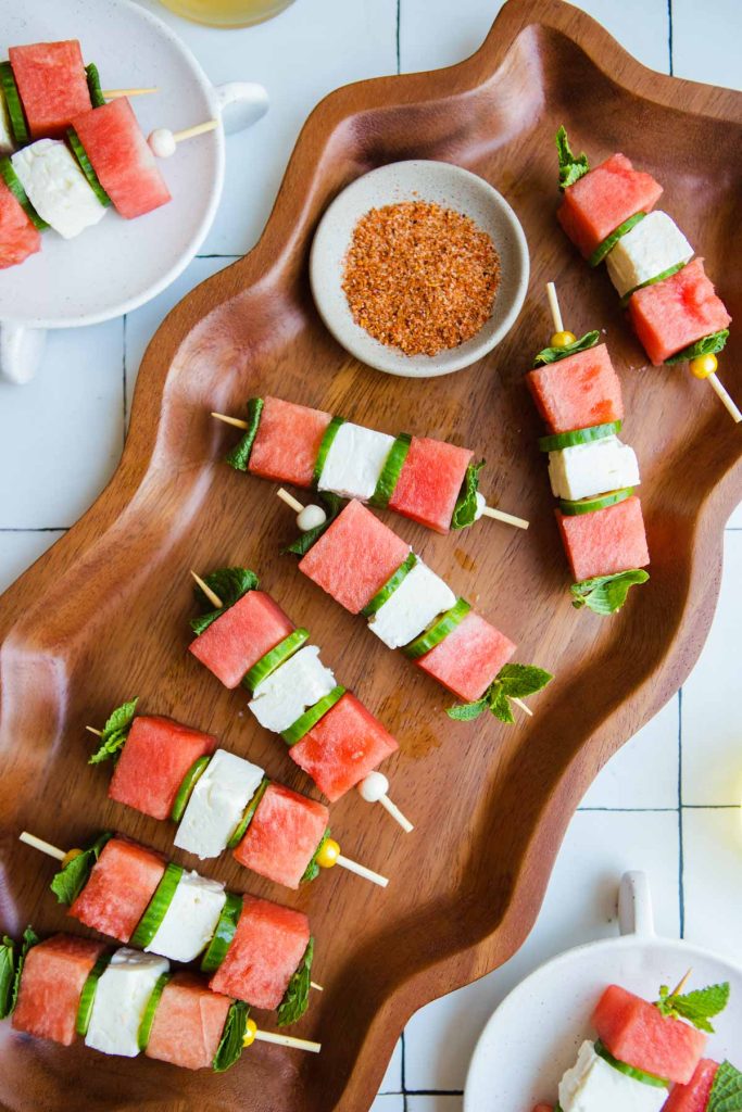 small watermelon feta skewers with cucumber and mint sprinkled with tajin on a wood platter