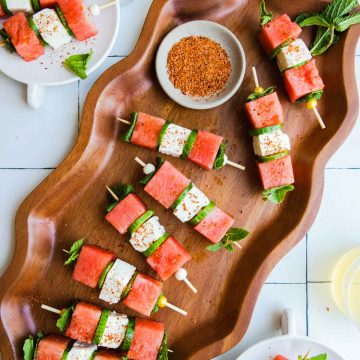 wavy platter with watermelon feta skewers placed on top and sprinkled with Tajin seasoning