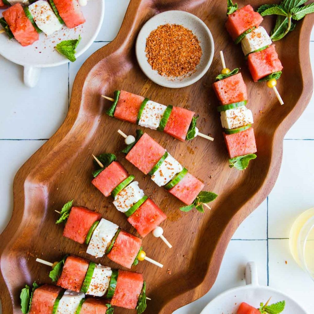 wood wavy platter filled with watermelon feta skewers sprinkled with tajin