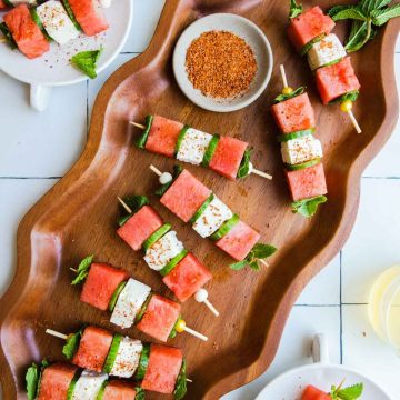 wood wavy platter filled with watermelon feta skewers sprinkled with tajin
