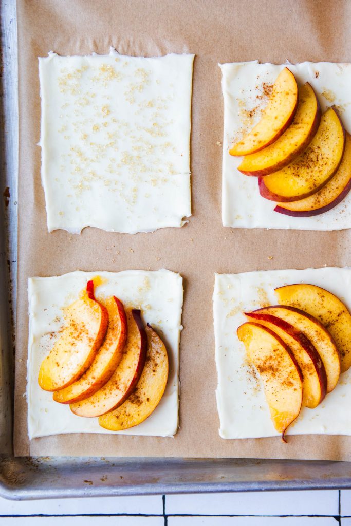 puff pastry squares with fresh peaches laid out on top and sprinkled with brown sugar