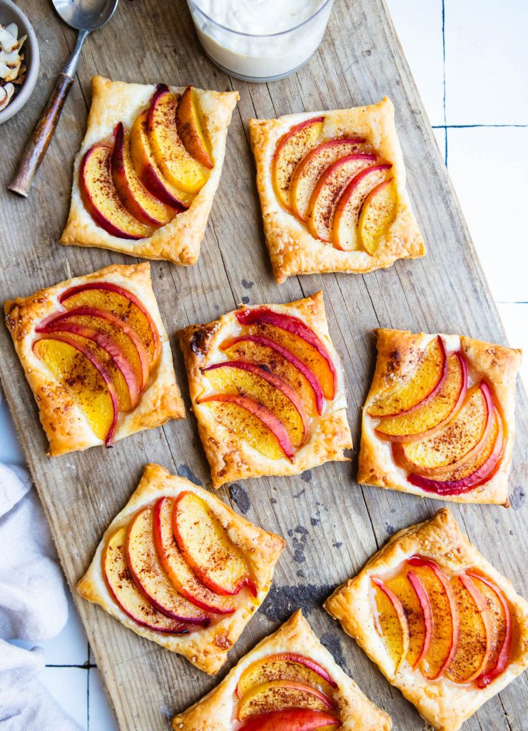 freshly bakes peach tarts on a wooden cutting board
