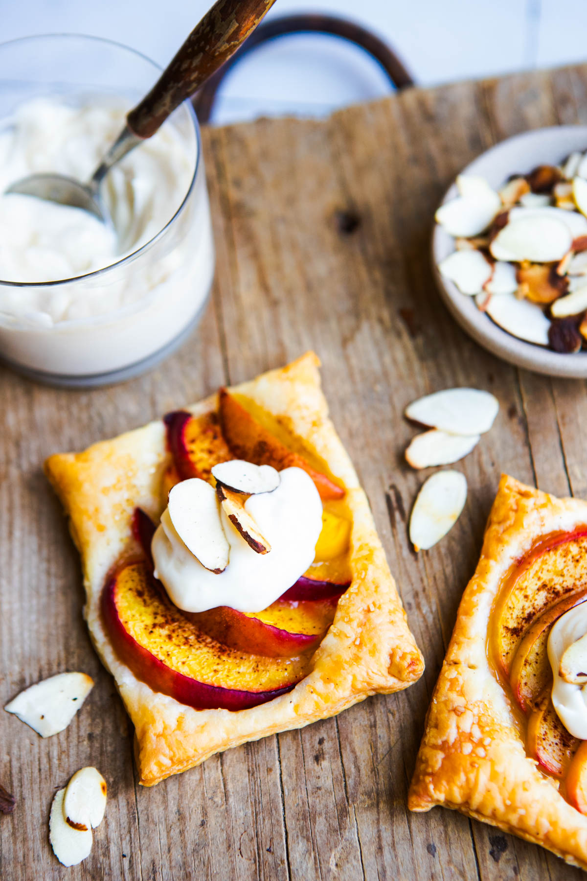 whipped light cream cheese topping next to a peach puff pastry tart