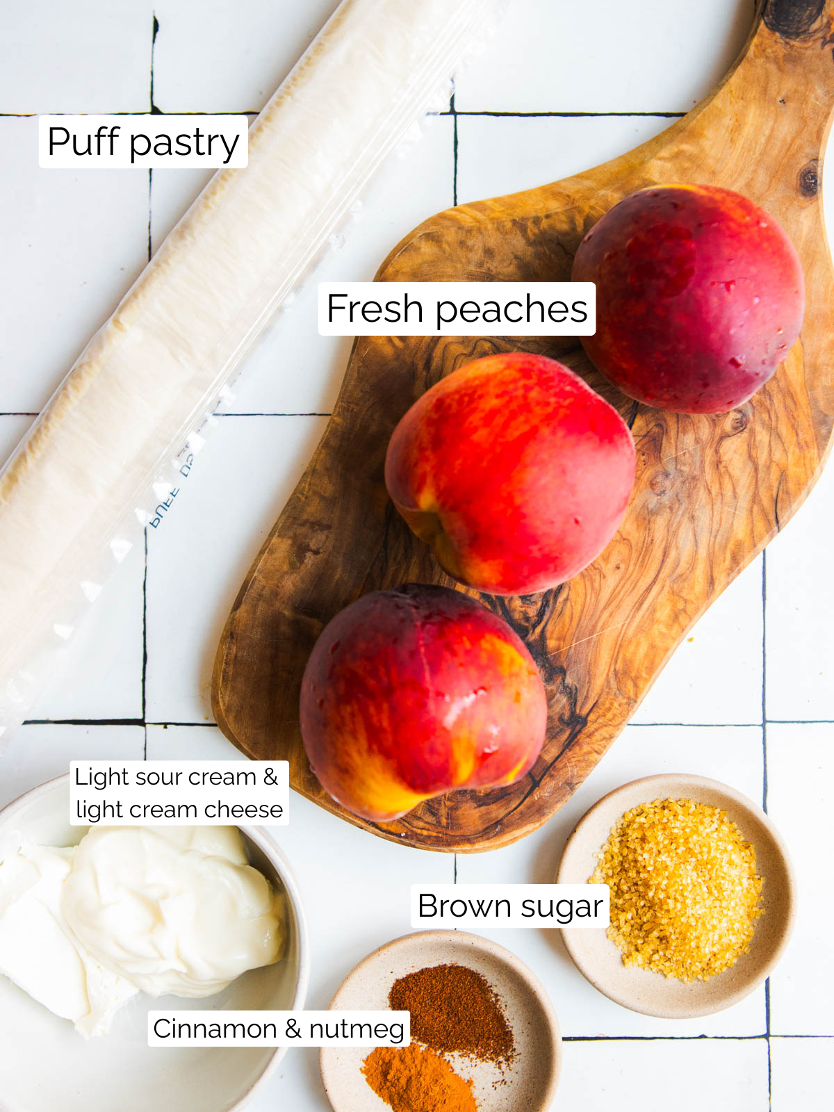 ingredients to make peach puff pastry tarts on a tile board