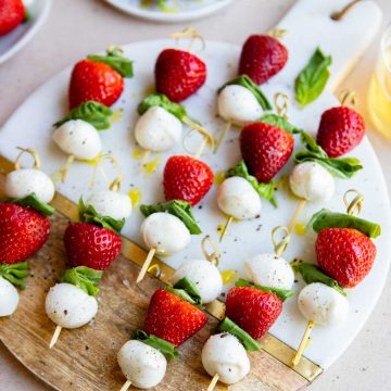 wood and marble board filled with strawberry and bocconcini skewers