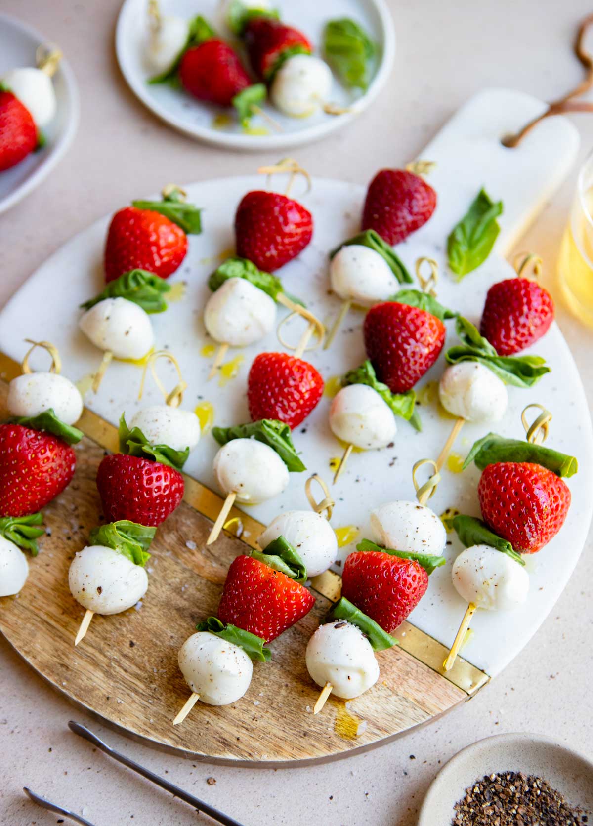wood and marble board filled with mini caprese skewers with strawberries and basil