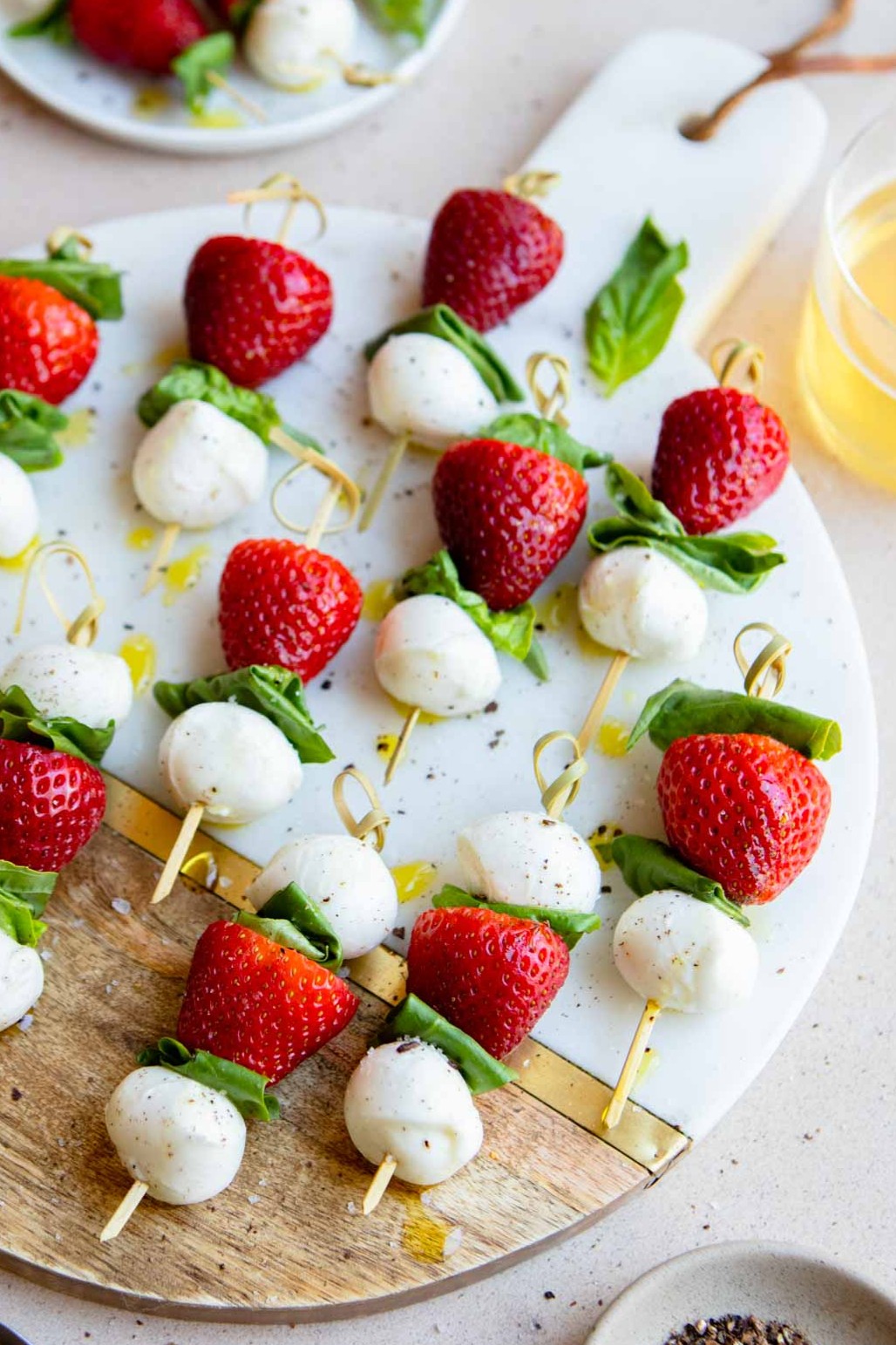 mini strawberry caprese skewers on a marble and wood board