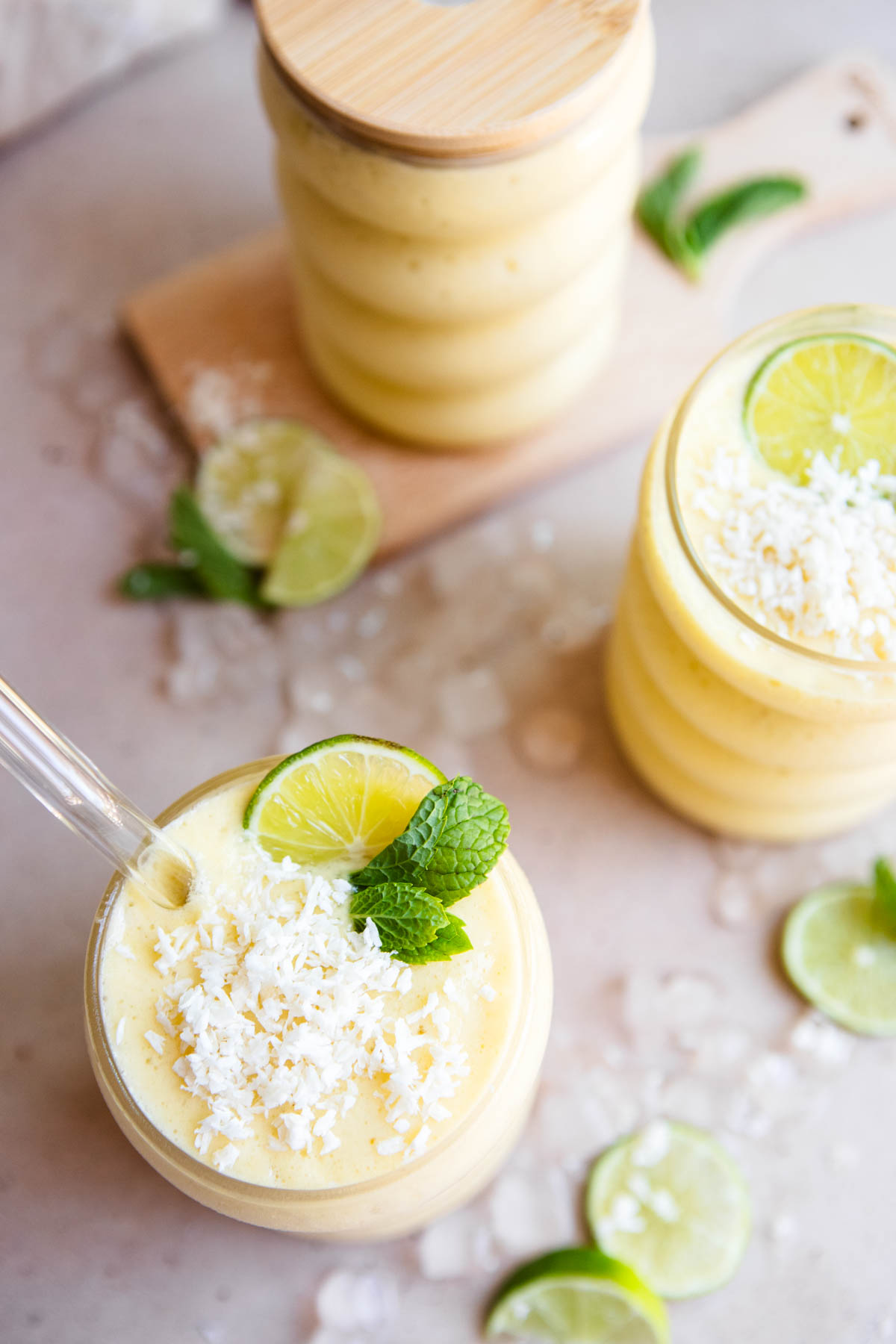 frozen mango smoothie garnished with coconut flakes and lime wedges 