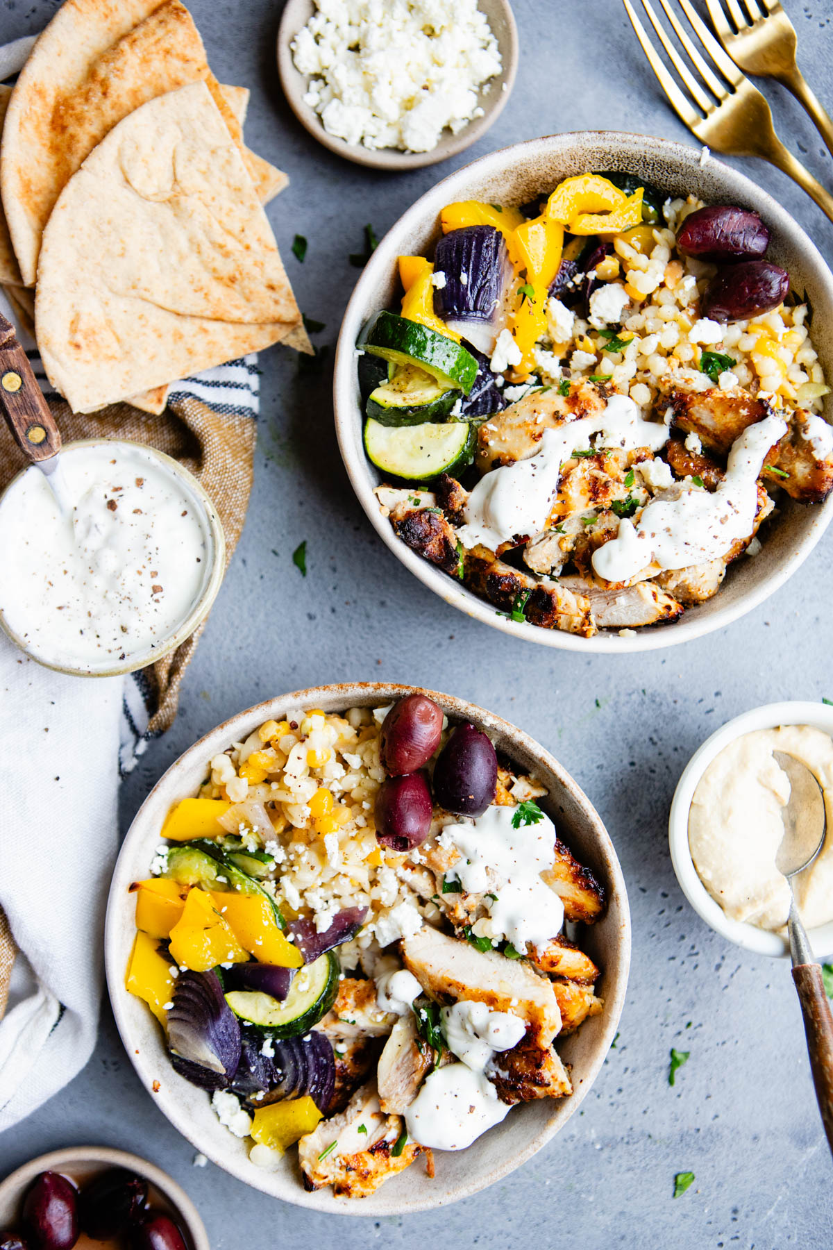 Mediterranean chicken bowls made with pearl couscous and roasted veggies in beige bowls