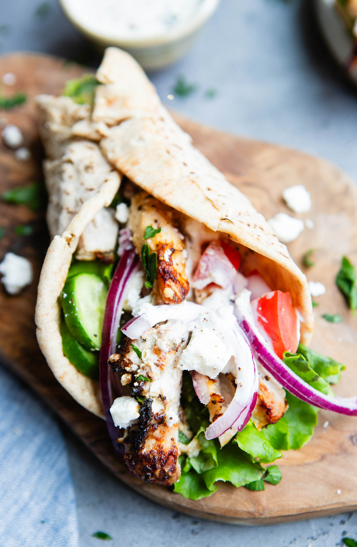 Mediterranean chicken wrap drizzled with garlic sauce on a wood board