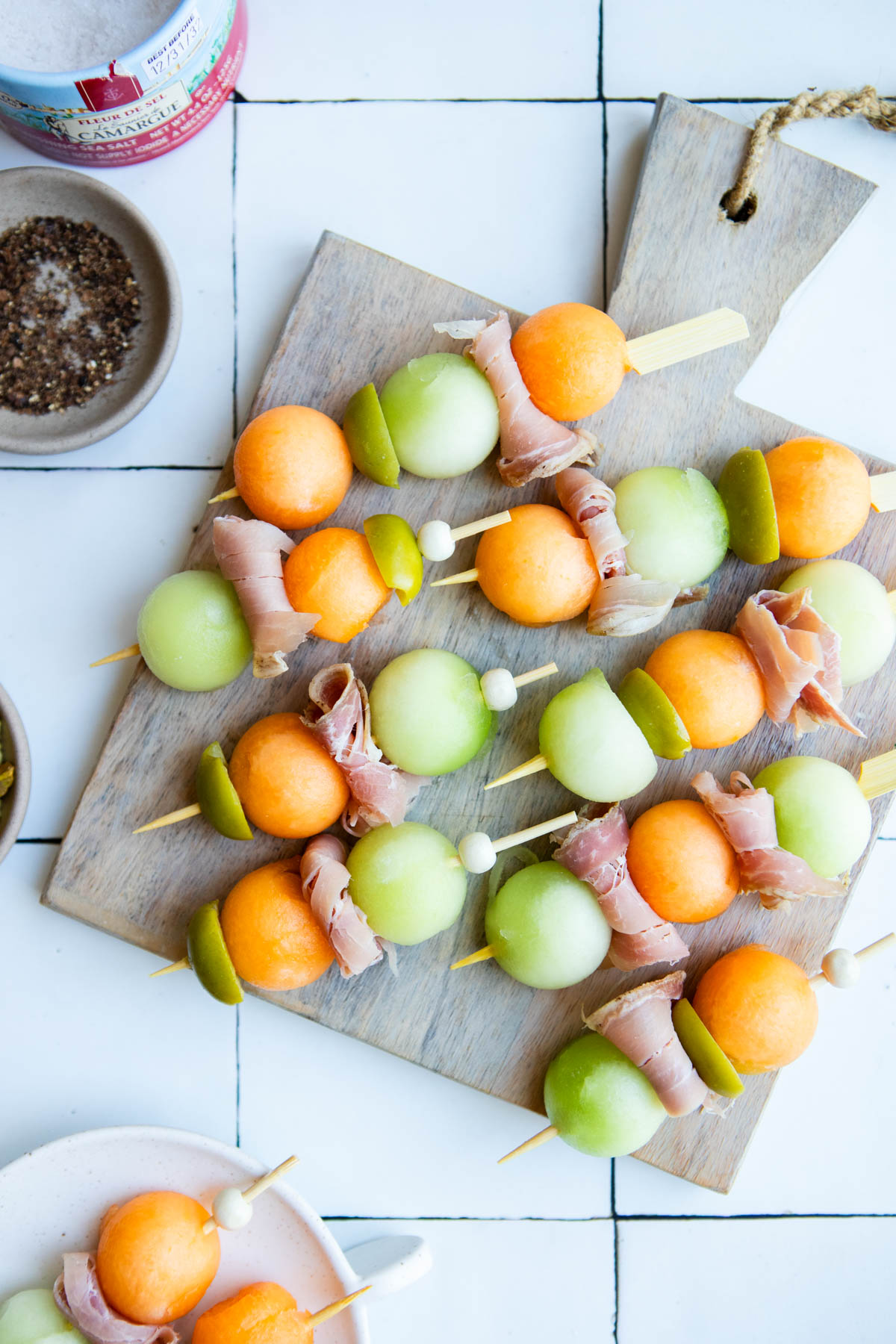 melon balls and thin slices of prosciutto on wooden skewers and served on a wood board