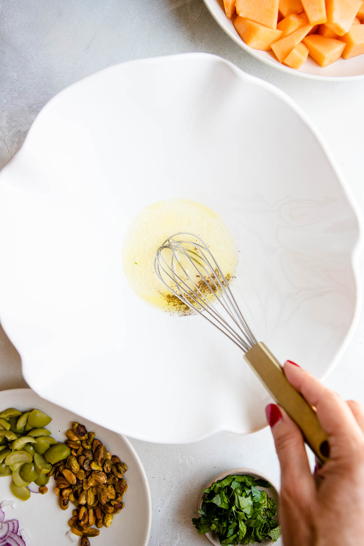 salad dressing ingredients whisked in a white ceramic serving bowl