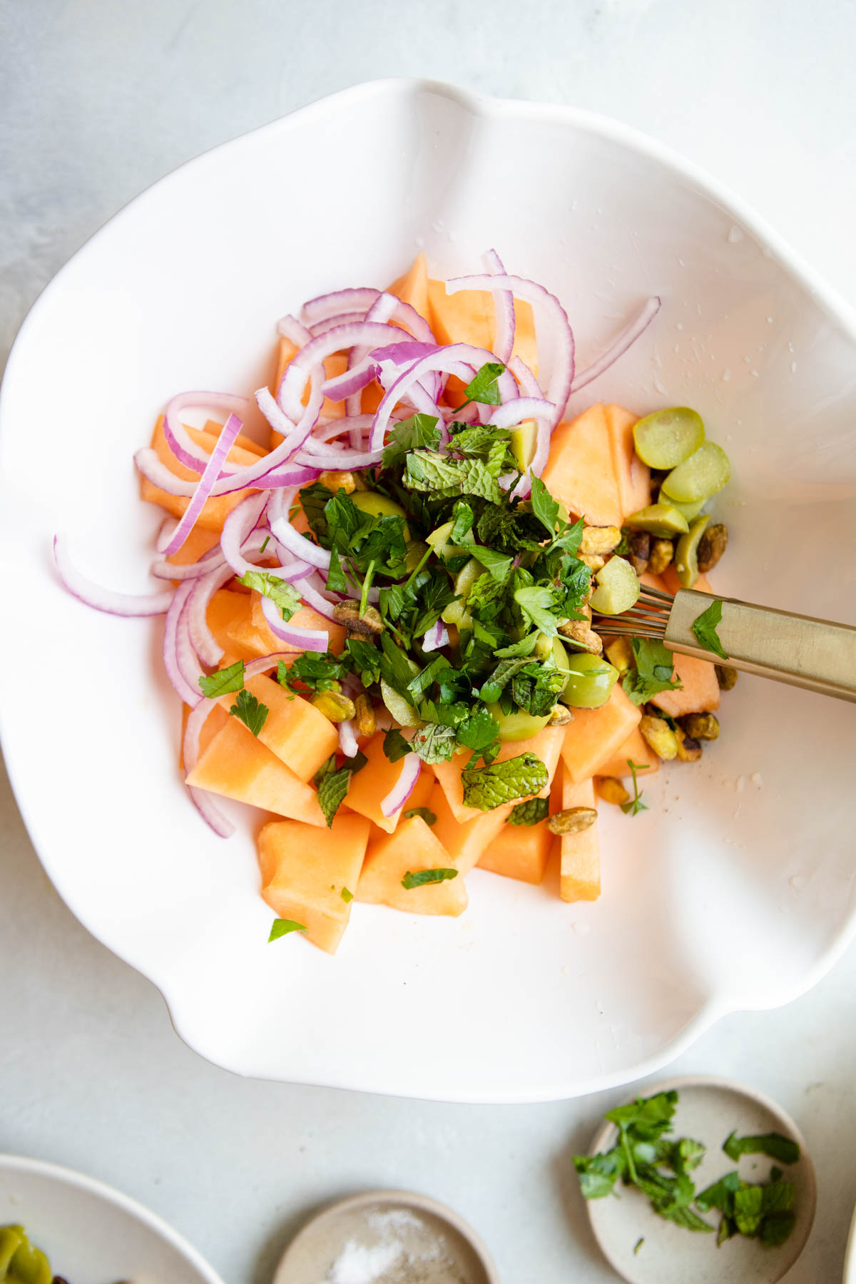 fresh cantaloupe and other ingredients added to a salad bowl to make a melon salad