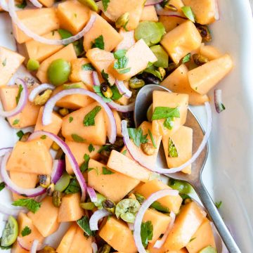 cantaloupe salad on a white platter with a large serving spoon
