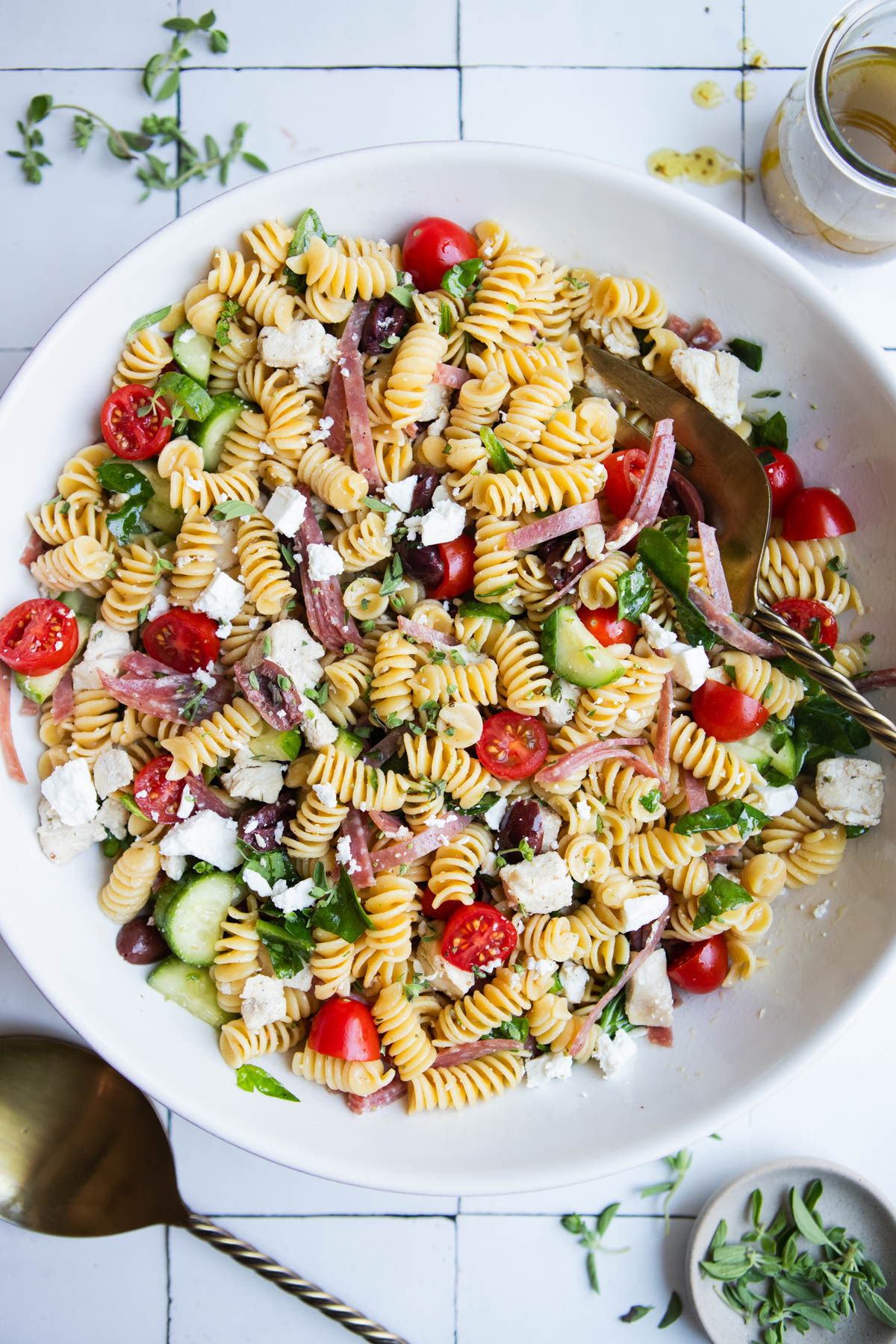 high protein pasta salad with feta and oregano salad dressing in a large white ceramic serving bowl
