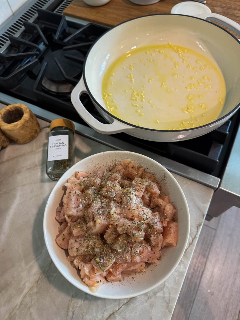cubed raw chicken sprinkled with Italian seasoning and ready to be cooked 