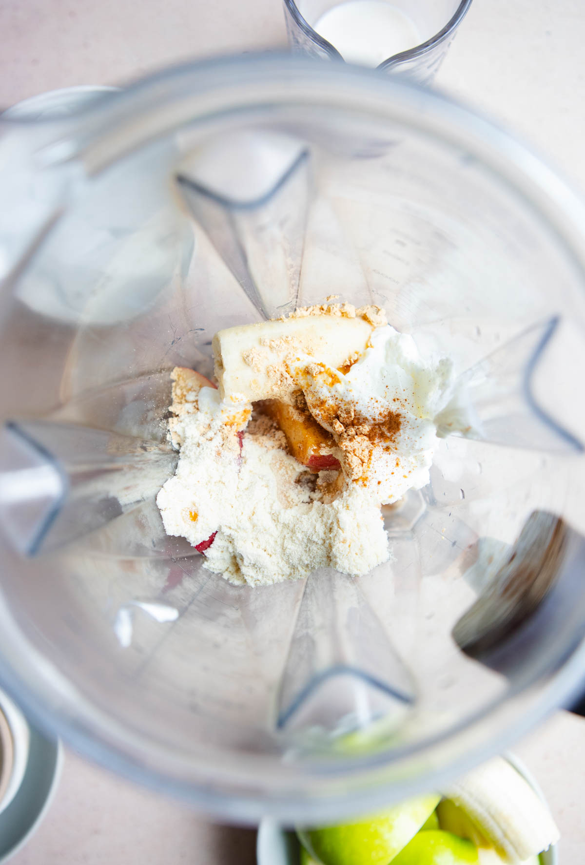 ingredients being added to a blender to make an apple cinnamon smoothie 
