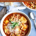 hearty and healthy pasta e fagioli recipe served in a large soup bowl and garnished with basil and parmesan cheese