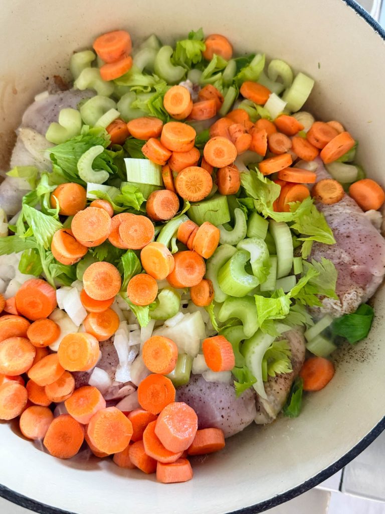 raw carrots and celery added a Dutch oven with seared chicken thighs and drumsticks