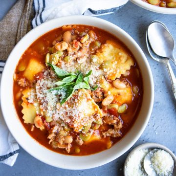 a white bow filled with pasta fagioli recipe made with ravioli and Italian chicken sausage