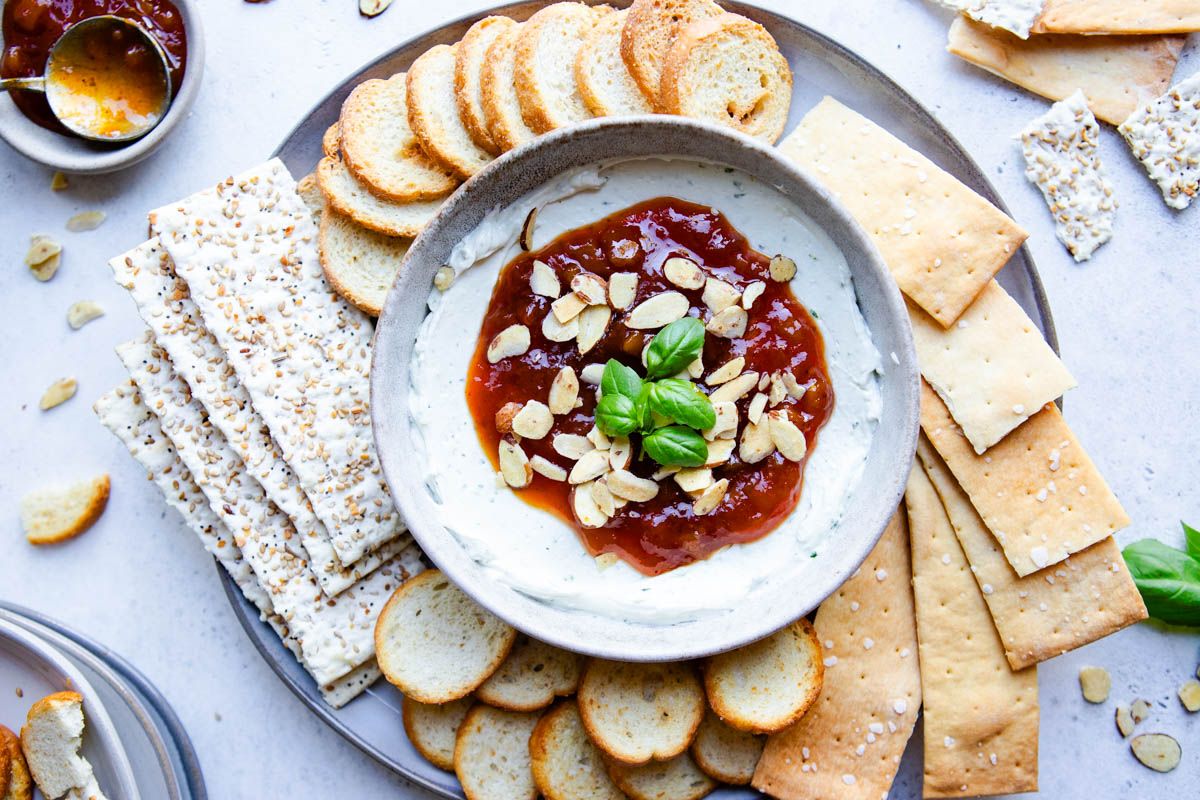 round white bowl filled with whipped goat cheese dip and topped with mango chutney