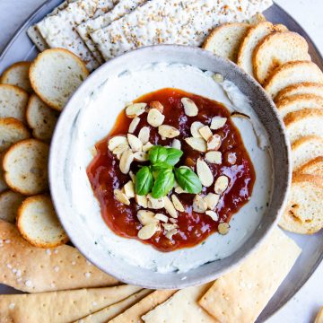 whipped goat cheese dip with mango chutney topping and crackers spread around the dip