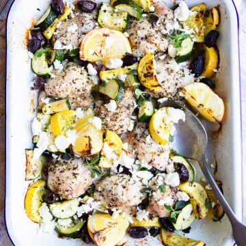 greek lemon chicken in a white pan and garnished with feta cheese