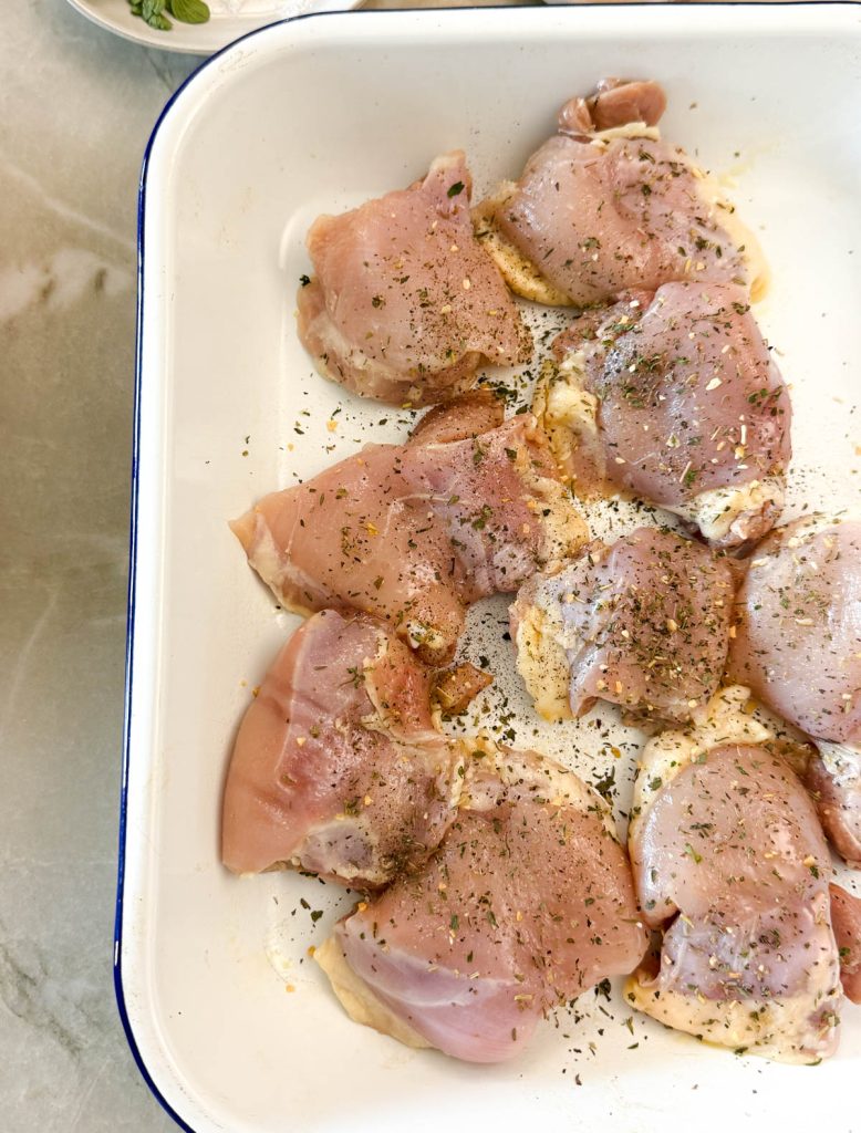 raw chicken thighs sprayed with olive oil and sprinkled with Greek seasoning