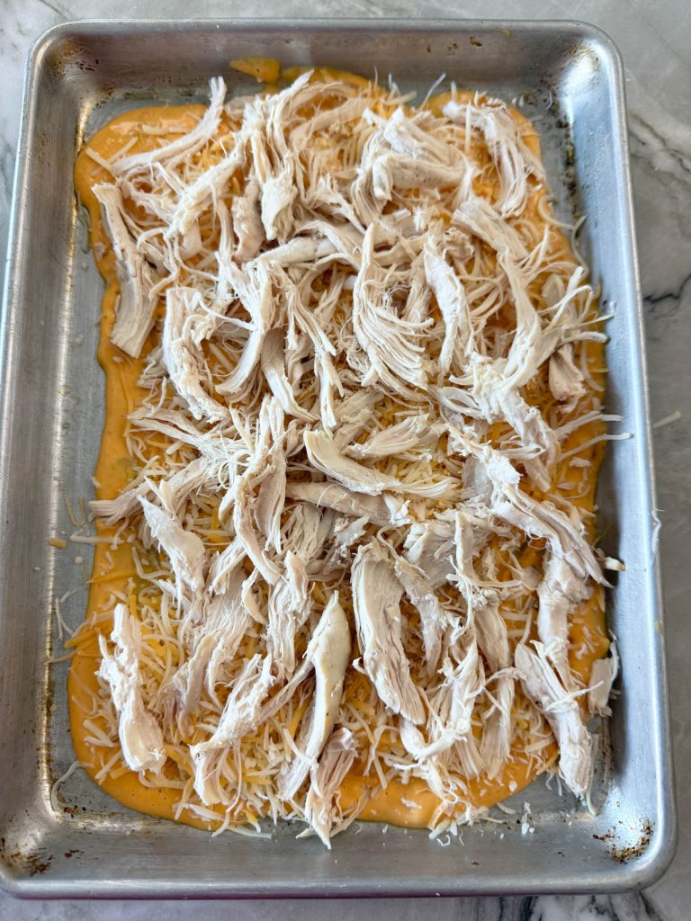 queso, shredded cheese and shredded chicken on a ¼ sheet pan