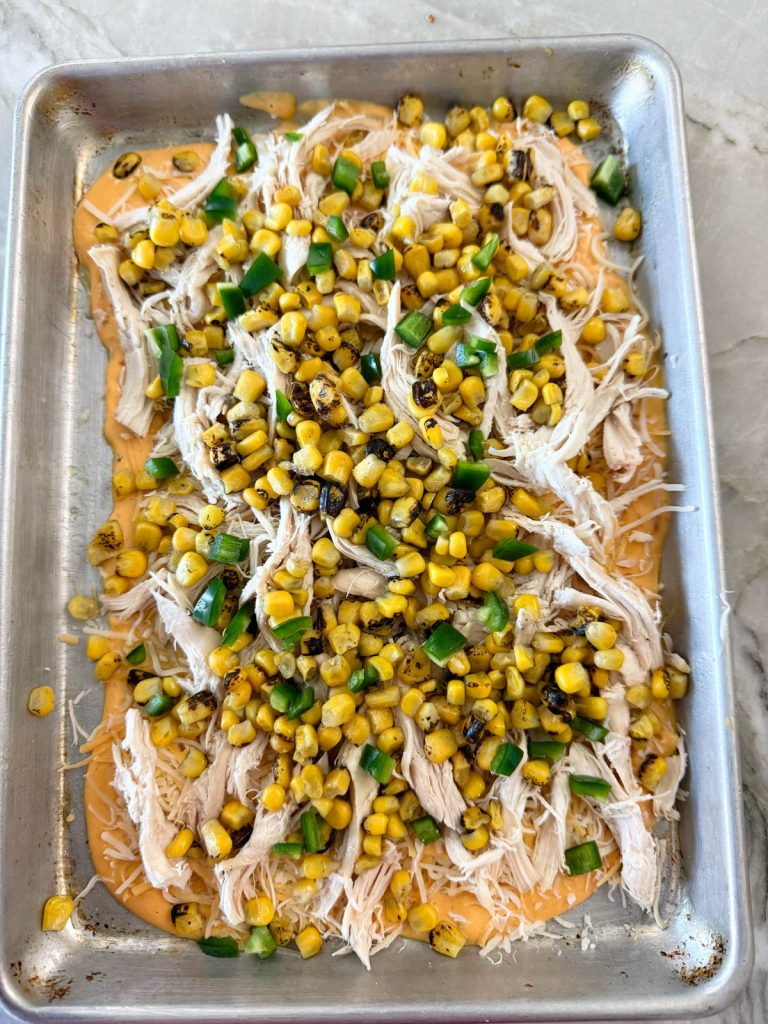 corn kernels and diced jalapeno on a tray of queso cheese