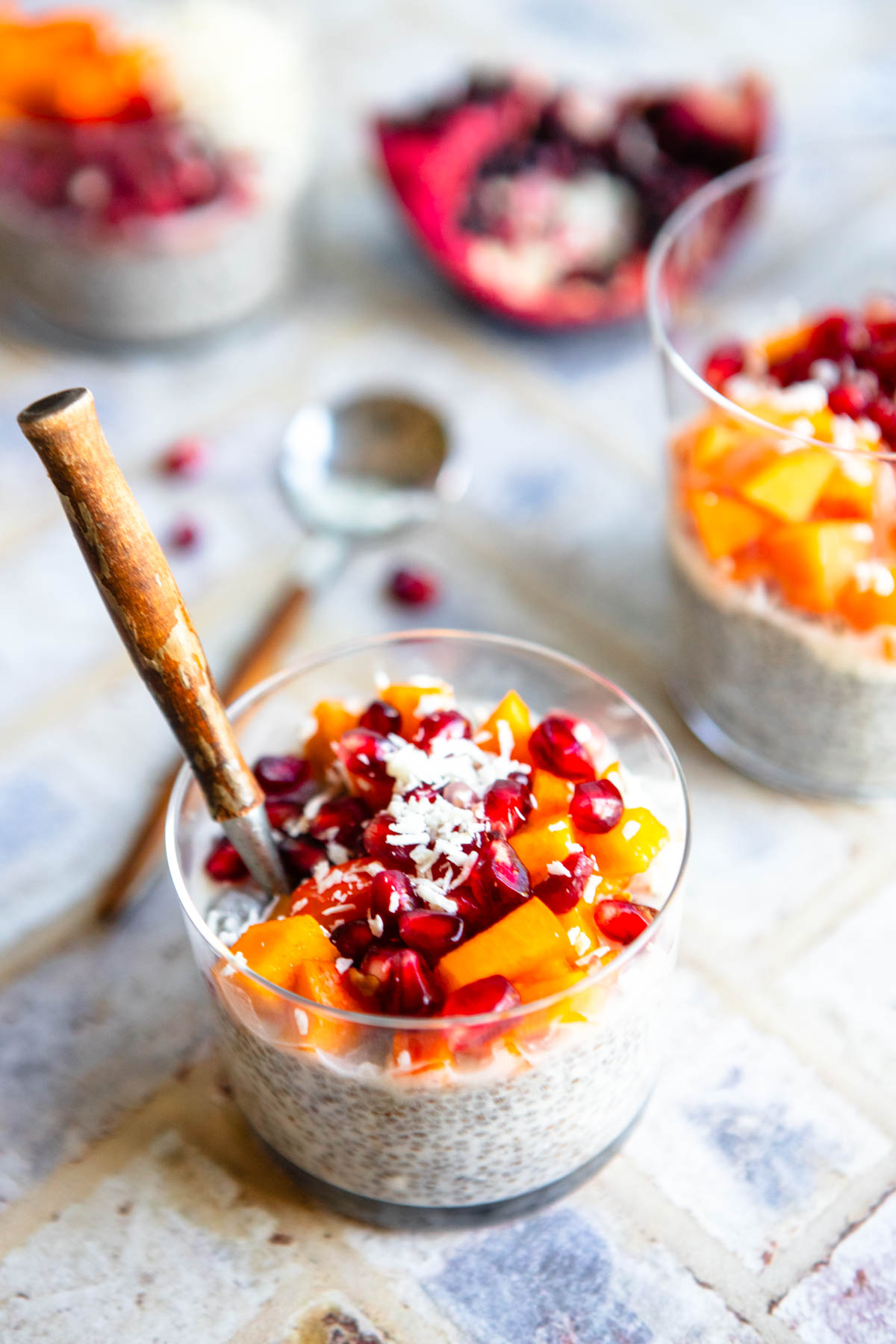 coconut chia seed pudding garnished with shredded coconut flakes, persimmons and pomegranates