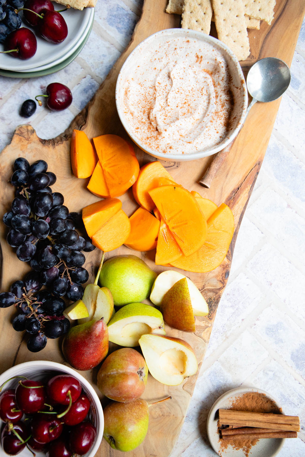 Greek yogurt fruit dip on a wooden board with various fruits