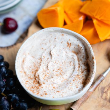 blended Greek yogurt fruit dip in a small bowl next to a pile of delicious fruit